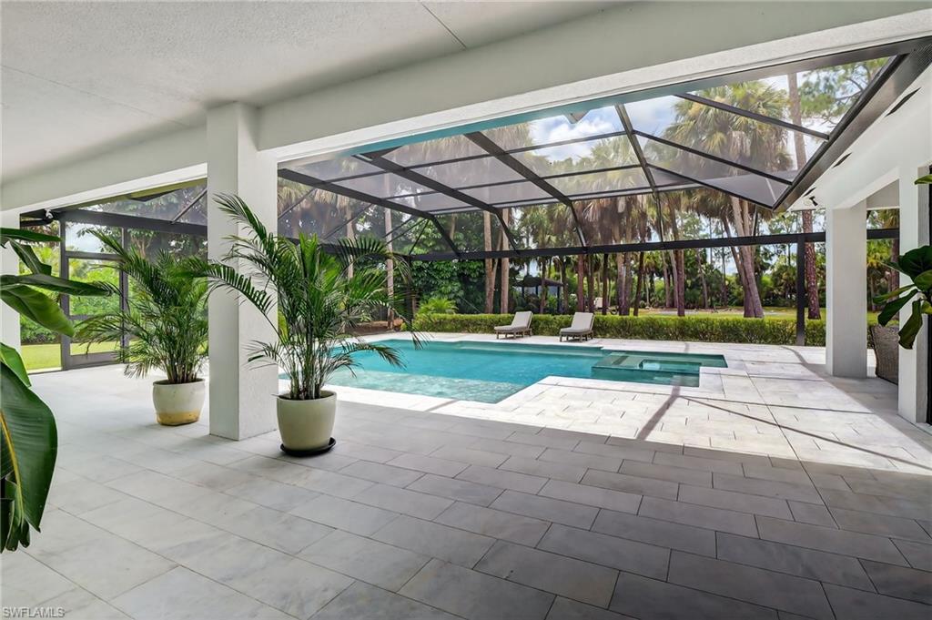 Outdoor pool featuring a patio, a sunroom, and glass enclosure