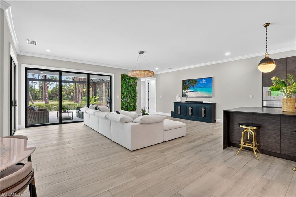 Living room featuring crown molding, light wood-type flooring, and recessed lighting