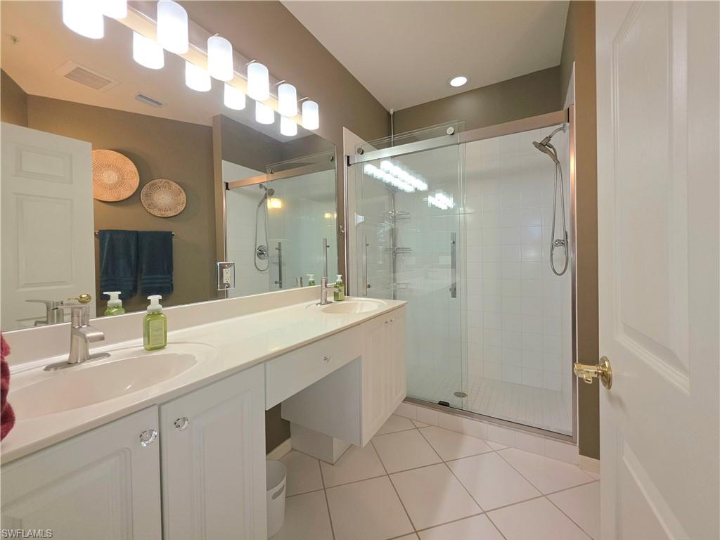 Full bathroom featuring double vanity, a shower stall, and light tile patterned floors