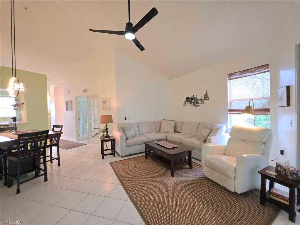 Living room featuring light tile patterned flooring, lofted ceiling, and ceiling fan
