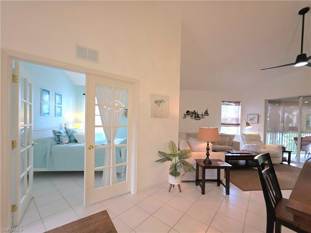 Living area with vaulted ceiling, ceiling fan, light tile patterned floors, and french doors