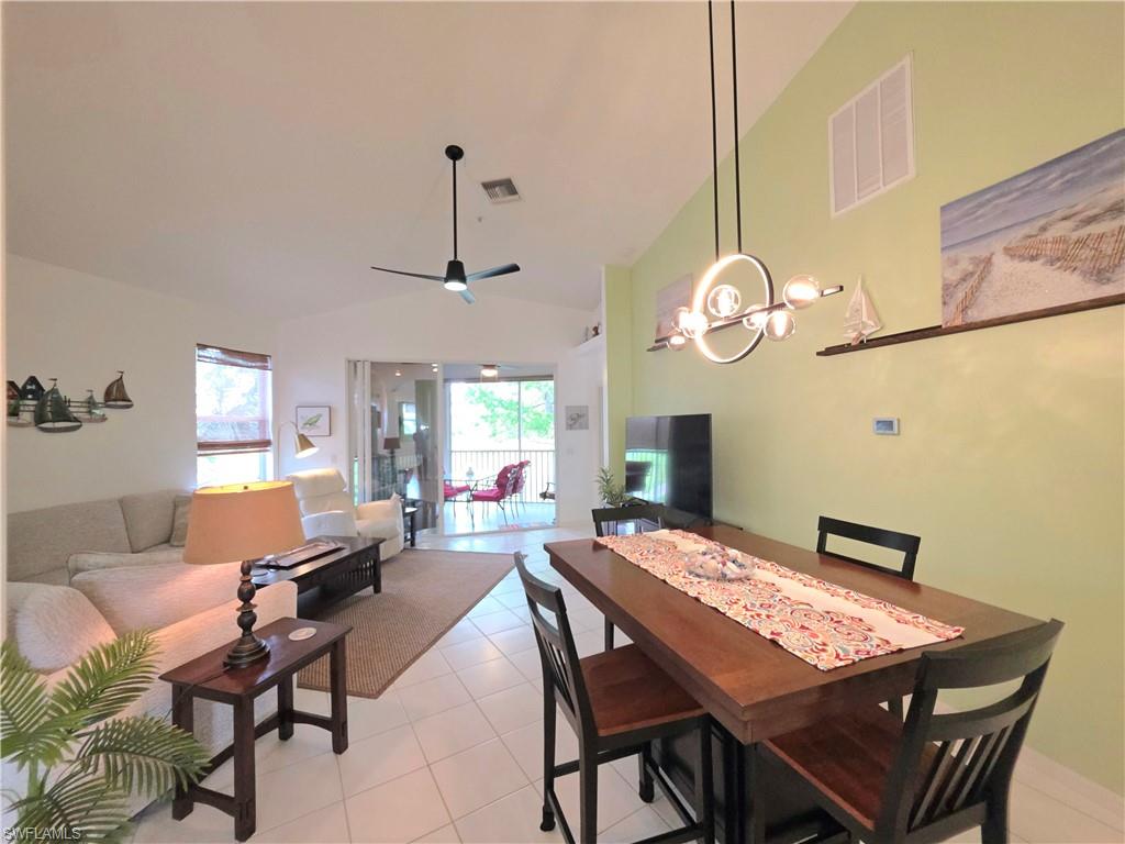 Dining space with vaulted ceiling, light tile patterned floors, and a ceiling fan