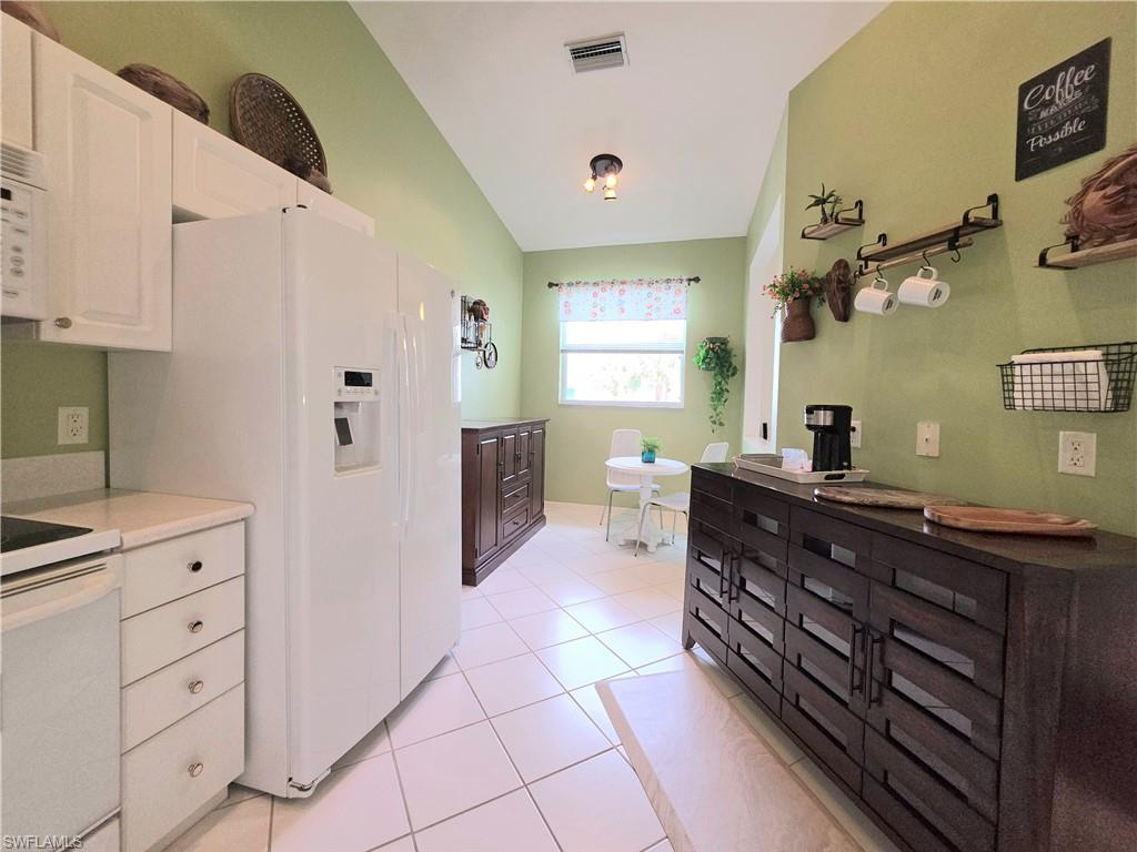 Full bathroom with light tile patterned floors, vaulted ceiling, and vanity