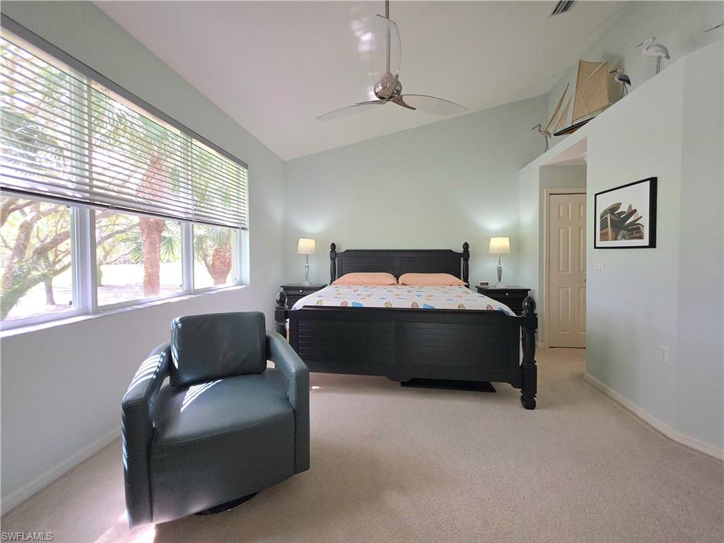 Bedroom featuring vaulted ceiling, light colored carpet, and ceiling fan