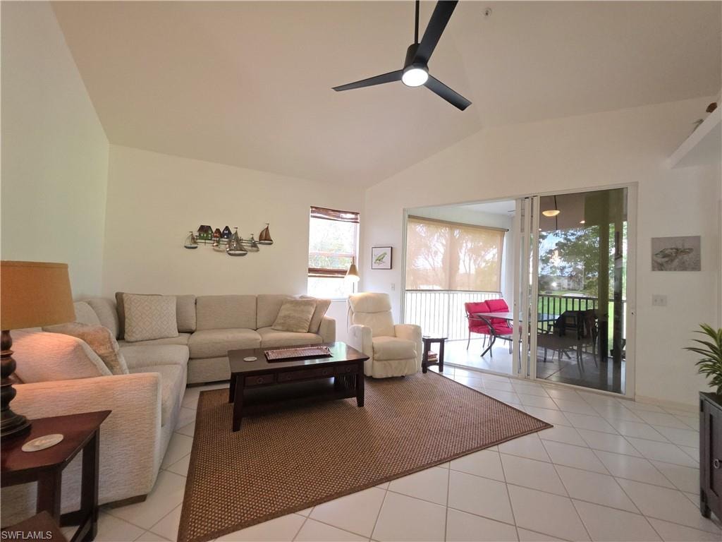 Living area featuring ceiling fan, light tile patterned flooring, and lofted ceiling
