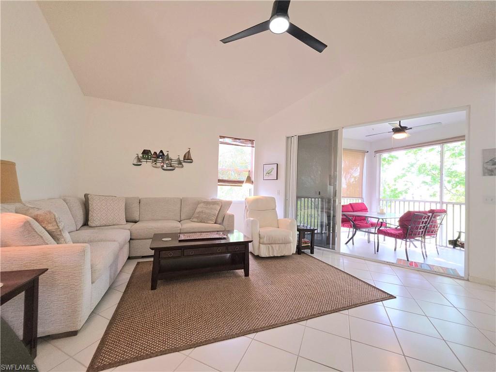 Living room featuring a ceiling fan, vaulted ceiling, and light tile patterned floors