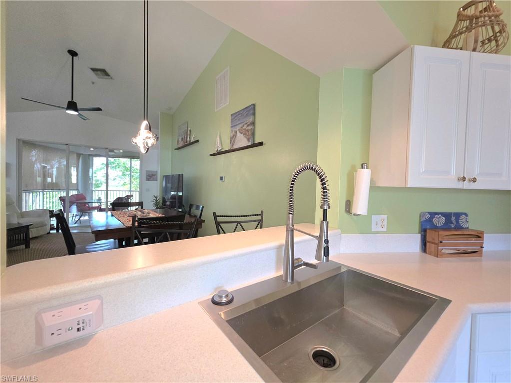 Kitchen featuring white cabinets, light countertops, lofted ceiling, ceiling fan, and hanging lights