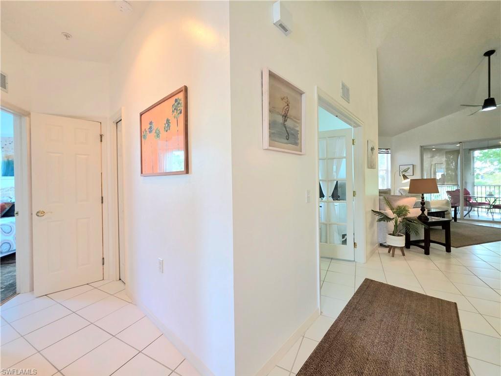 Hallway with light tile patterned flooring and vaulted ceiling