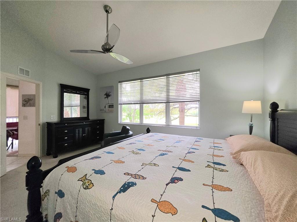 Carpeted bedroom featuring vaulted ceiling and a ceiling fan