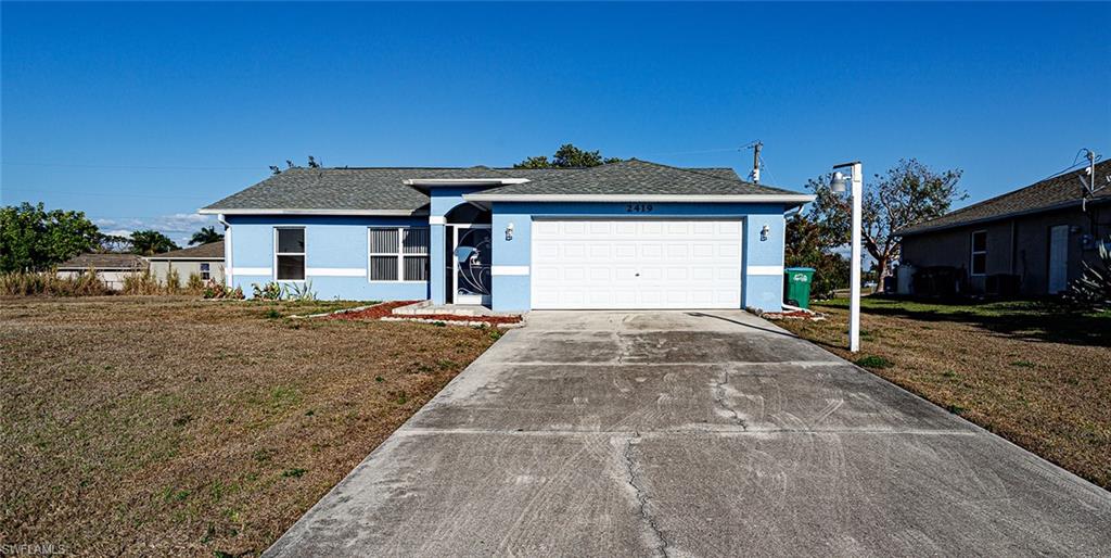 Ranch-style home with stucco siding, a front lawn, driveway, an attached garage, and roof with shingles