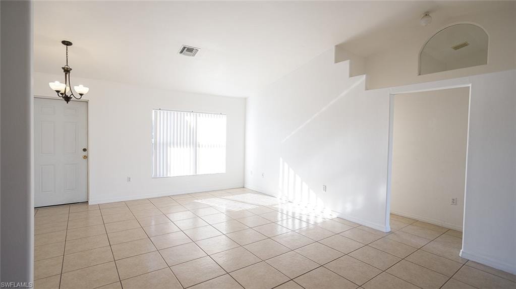 Spare room with hanging lights and light tile patterned flooring