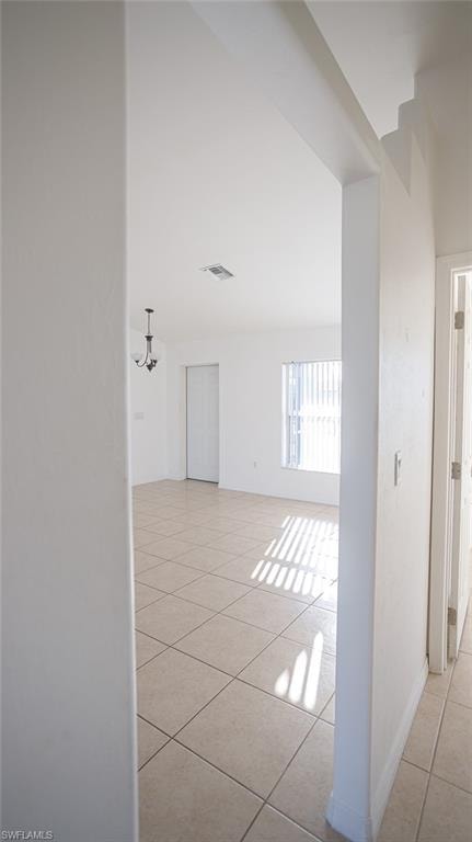 Corridor featuring light tile patterned floors, hanging lights, and a high ceiling