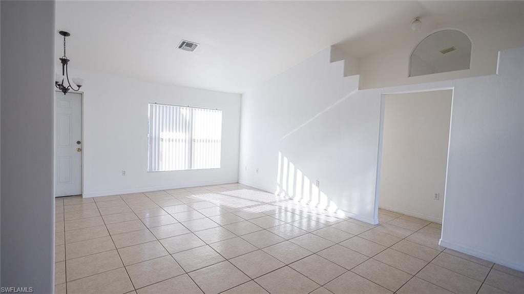 Empty room featuring light tile patterned floors and suspended lighting