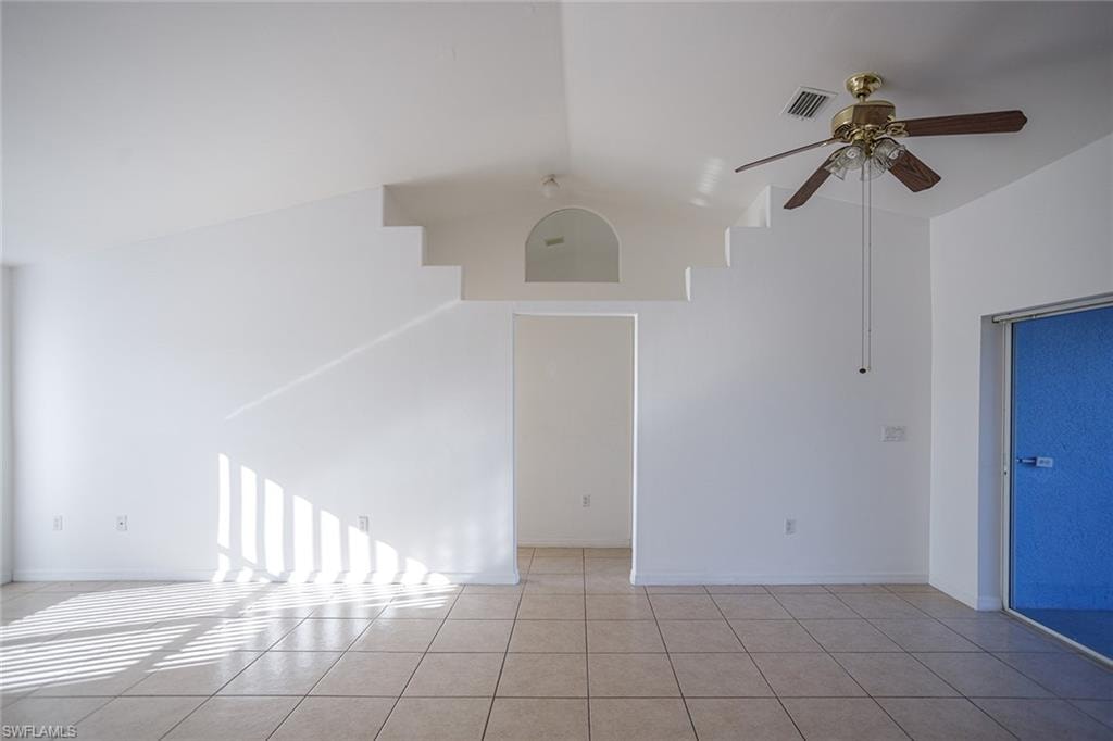 Unfurnished room featuring ceiling fan, lofted ceiling, and light tile patterned floors
