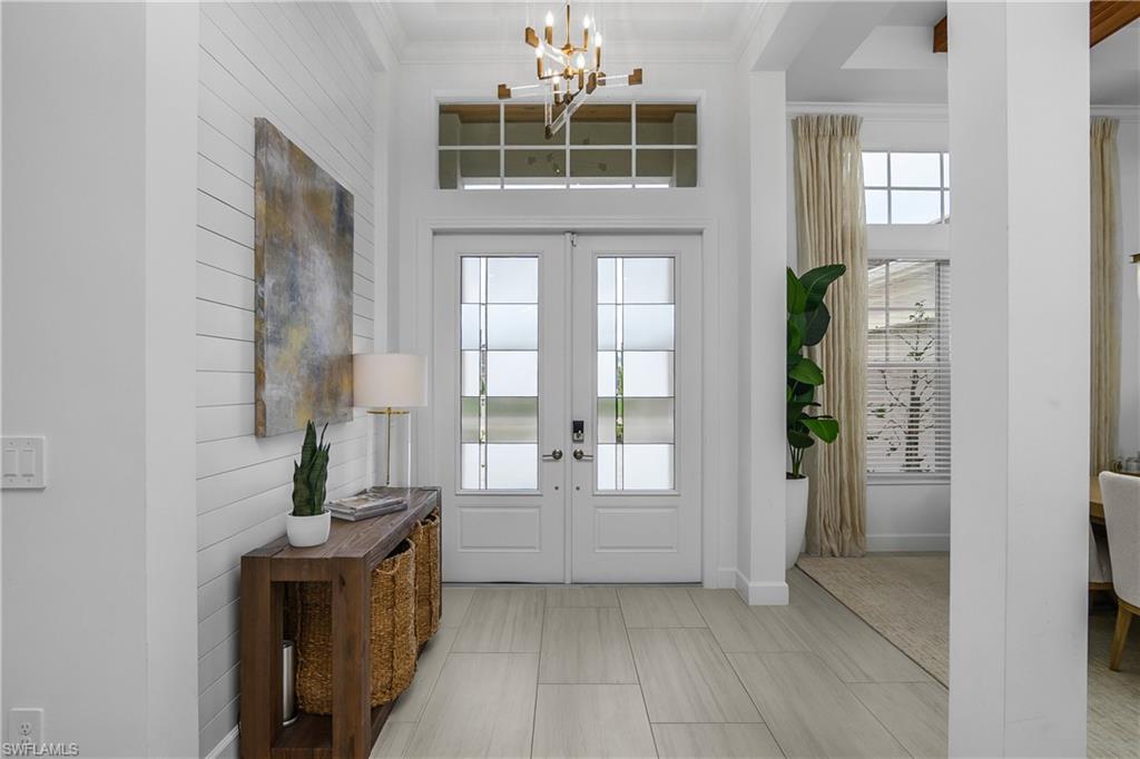 Entrance foyer featuring suspended lighting, ornamental molding, french doors, and wooden walls