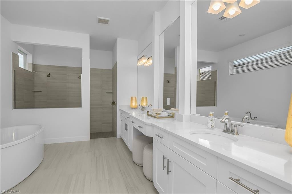 Bathroom featuring a walk in shower, a soaking tub, and double vanity