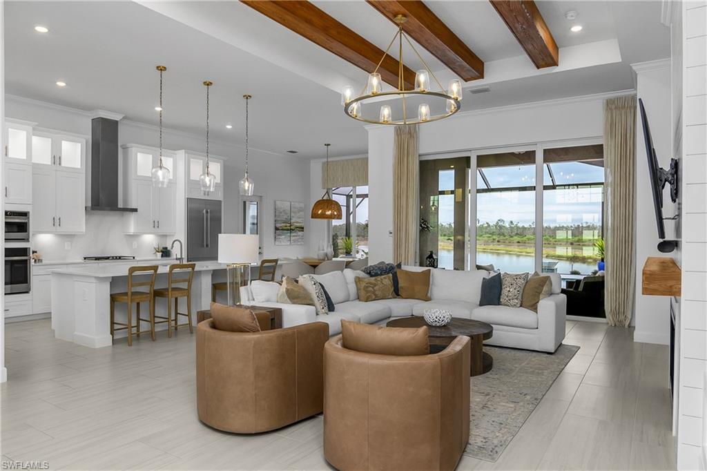 Living room featuring beamed ceiling, ornamental molding, and suspended lighting