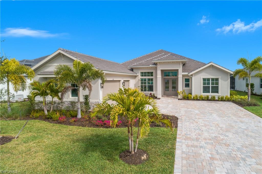 View of front of property featuring a garage, french doors, a front lawn, and decorative driveway