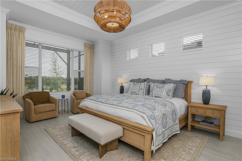 Bedroom with wooden walls, a tray ceiling, and crown molding