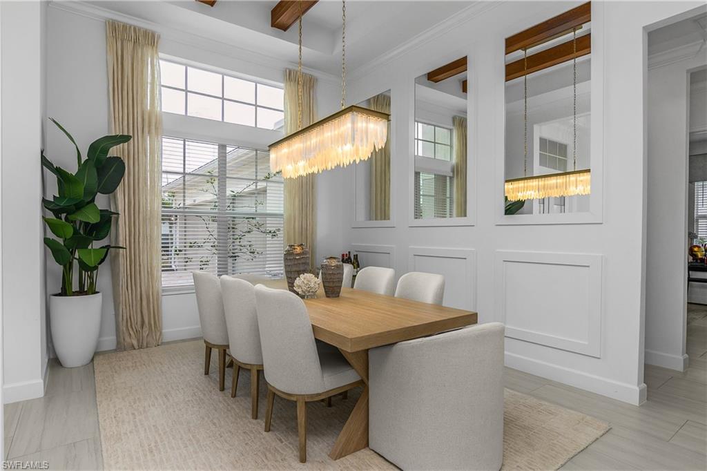 Dining area with crown molding, a decorative wall, and a chandelier