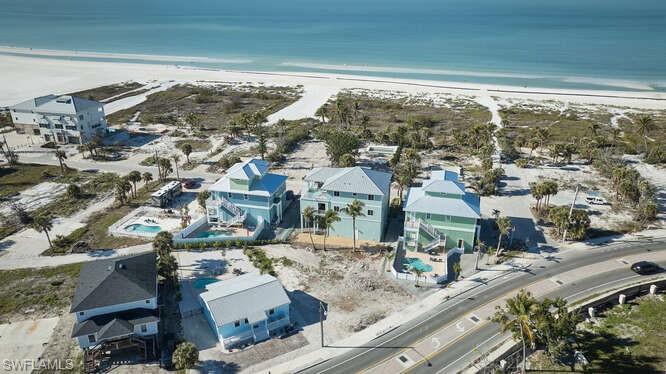 Birds eye view of property with a water view and a view of the beach