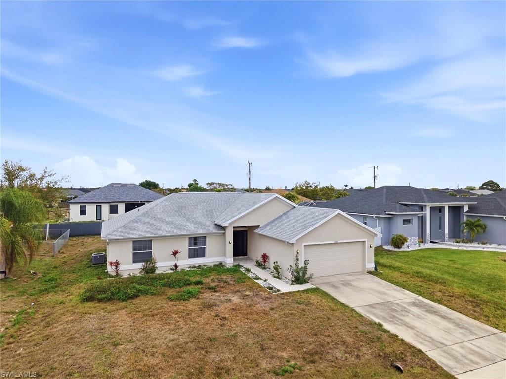Single story home with stucco siding, an attached garage, a front yard, concrete driveway, and roof with shingles