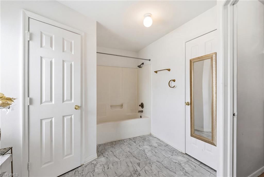 Bathroom with bathtub / shower combination and light marble finish floors