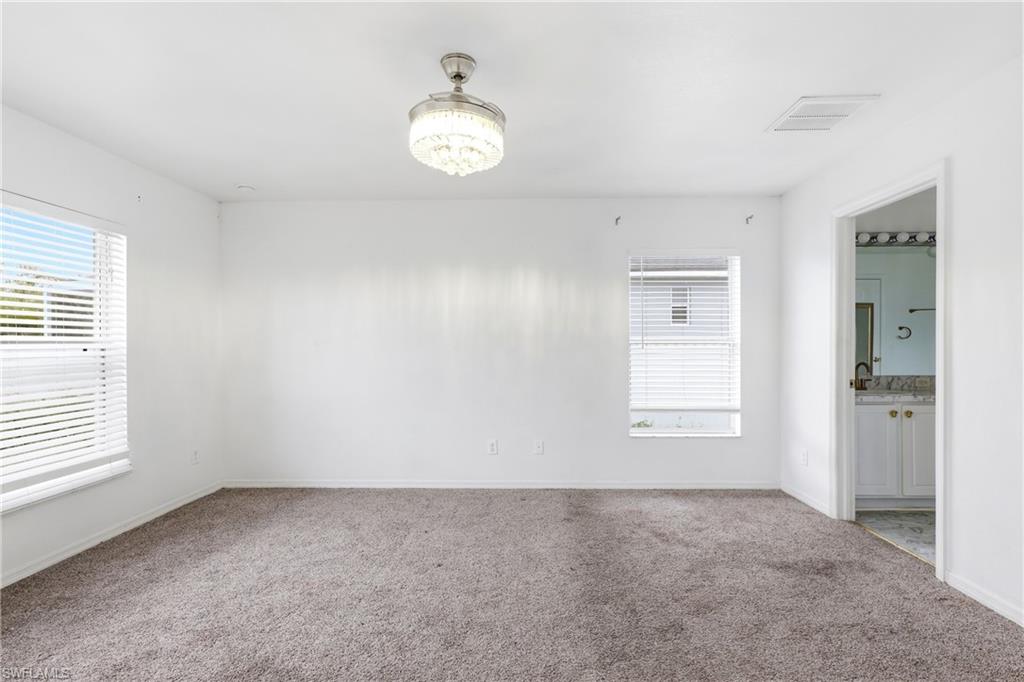 Carpeted empty room with suspended lighting and baseboards