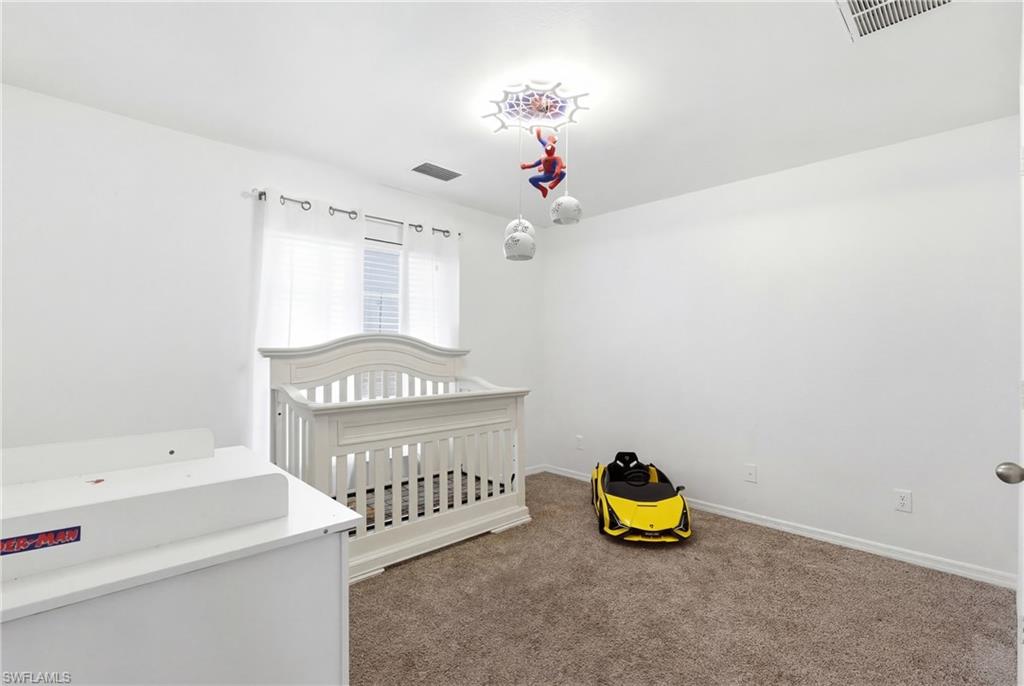 Unfurnished bedroom with dark carpet and a nursery area