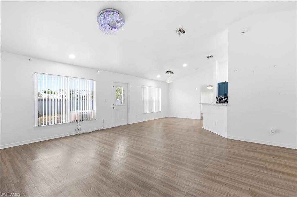Unfurnished living room featuring vaulted ceiling, dark wood finished floors, and recessed lighting