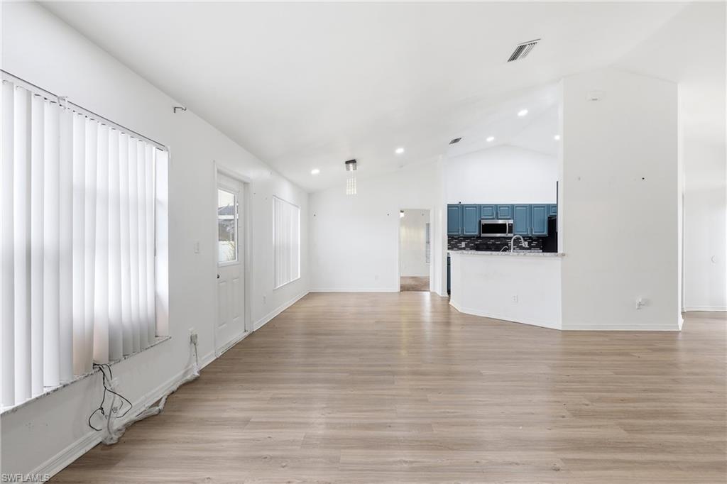 Unfurnished living room with light wood-type flooring, vaulted ceiling, and recessed lighting