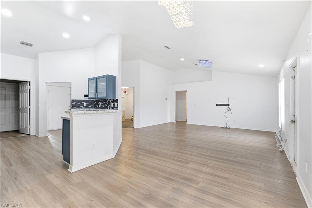 Kitchen with open floor plan, lofted ceiling, recessed lighting, light stone countertops, and light wood-style floors