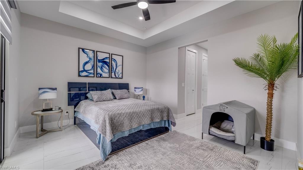 Primary Bedroom featuring a ceiling fan and a tray ceiling