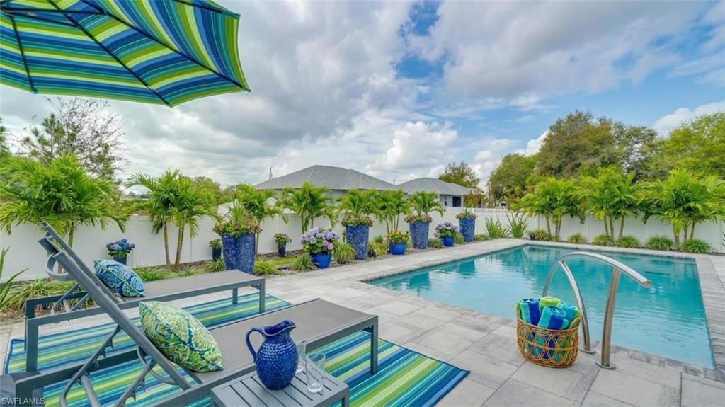 View of pool with pavered deck and a fenced backyard (Virtually enhanced)