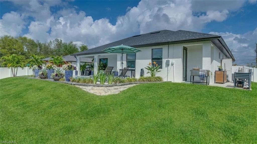 Back of property featuring a patio area, pool, tropical landscaping, and privacy fence. (Virtually enhanced)