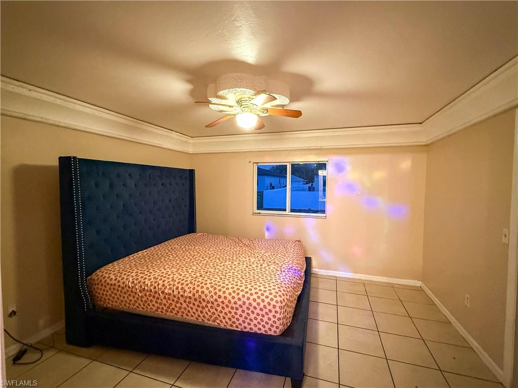 Bedroom featuring a ceiling fan, ornamental molding, and light tile patterned floors