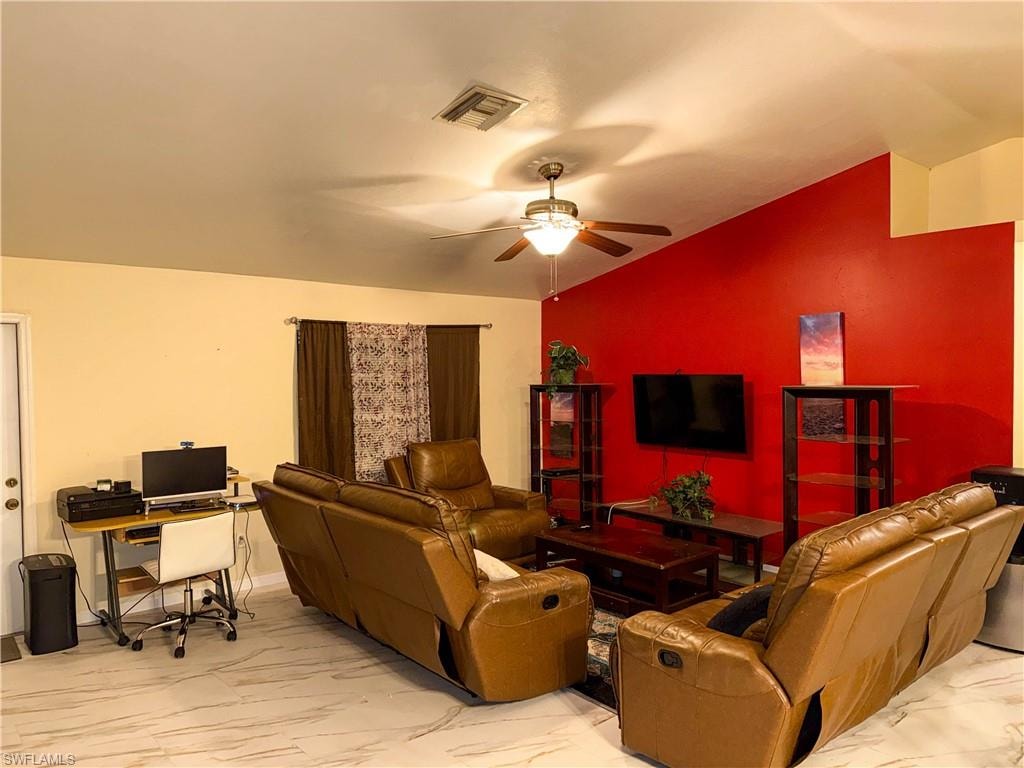 Living room with lofted ceiling, a desk, ceiling fan, and light marble finish floors
