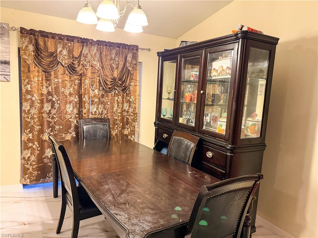 Dining area with a chandelier and light marble finish floors