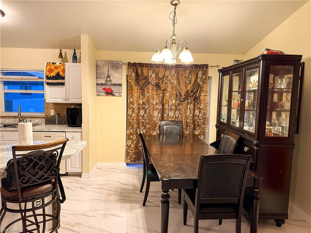 Dining area featuring a chandelier and light marble finish flooring