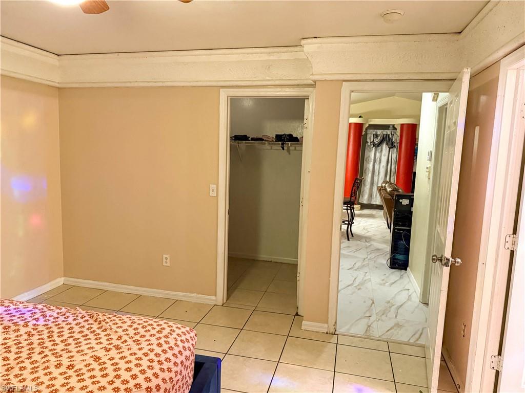 Bedroom with light tile patterned flooring and a walk in closet