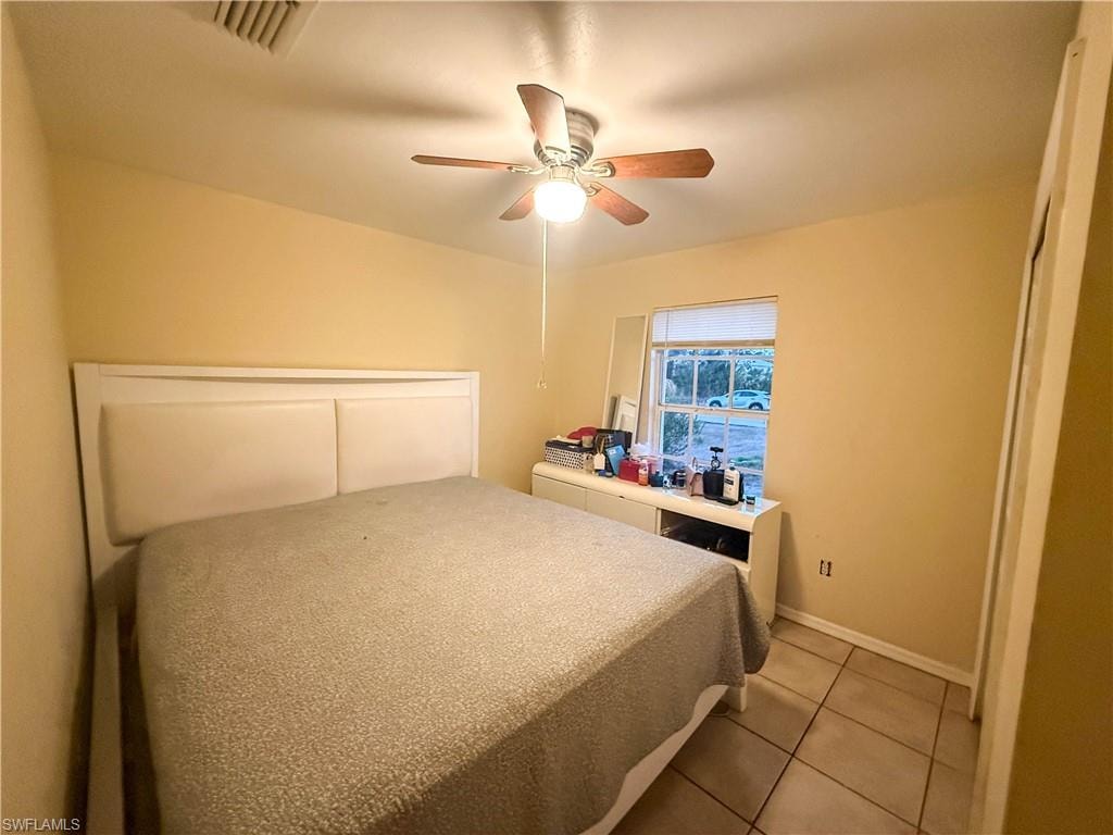 Bedroom featuring a ceiling fan, light tile patterned floors, and a closet