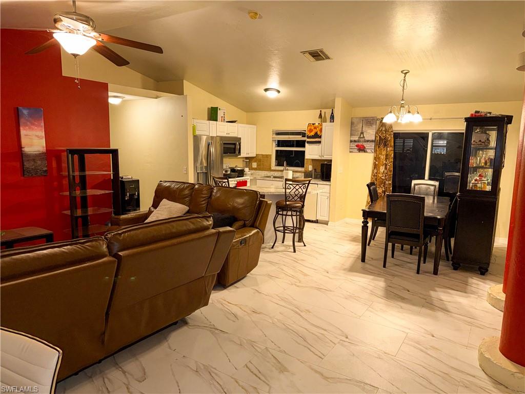 Living area with light marble finish floors, lofted ceiling, ceiling fan, and suspended lighting