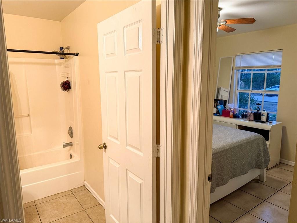 Bathroom featuring light tile patterned flooring, bathing tub / shower combination, and ceiling fan