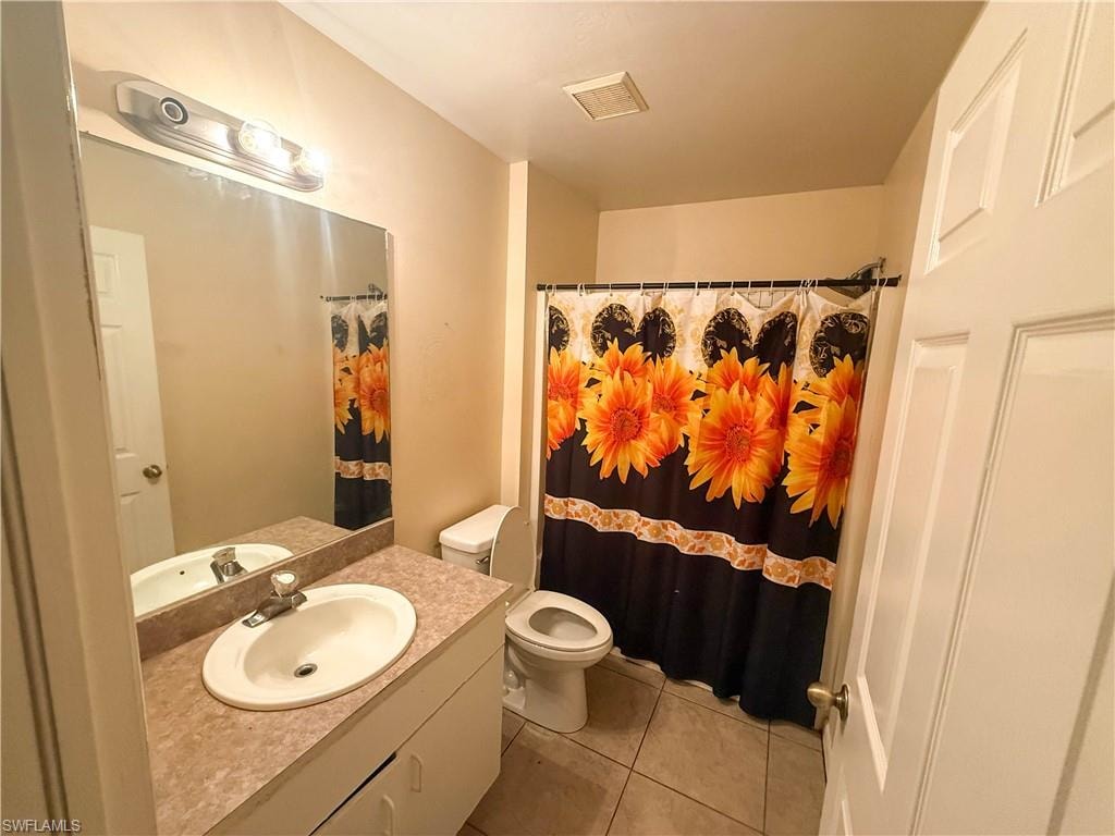 Bathroom with vanity, light tile patterned floors, and curtained shower