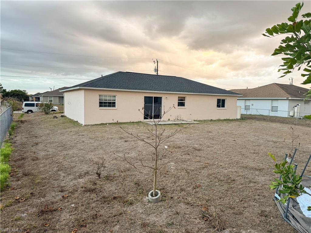 Rear view of property with stucco siding and a shingled roof