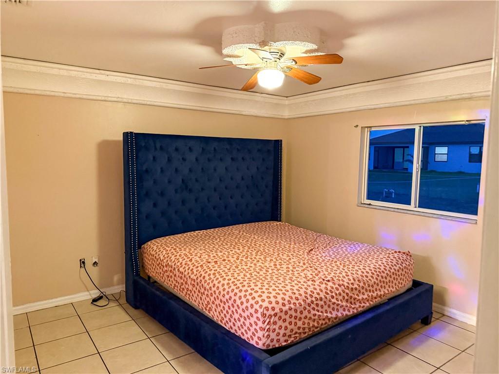Bedroom featuring a ceiling fan, ornamental molding, and light tile patterned floors
