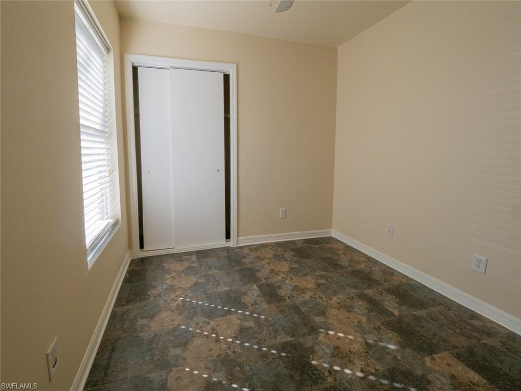 Unfurnished bedroom with a closet, multiple windows, and ceiling fan