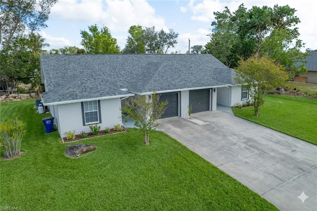 Single story home featuring a front lawn, a shingled roof, a garage, and stucco siding