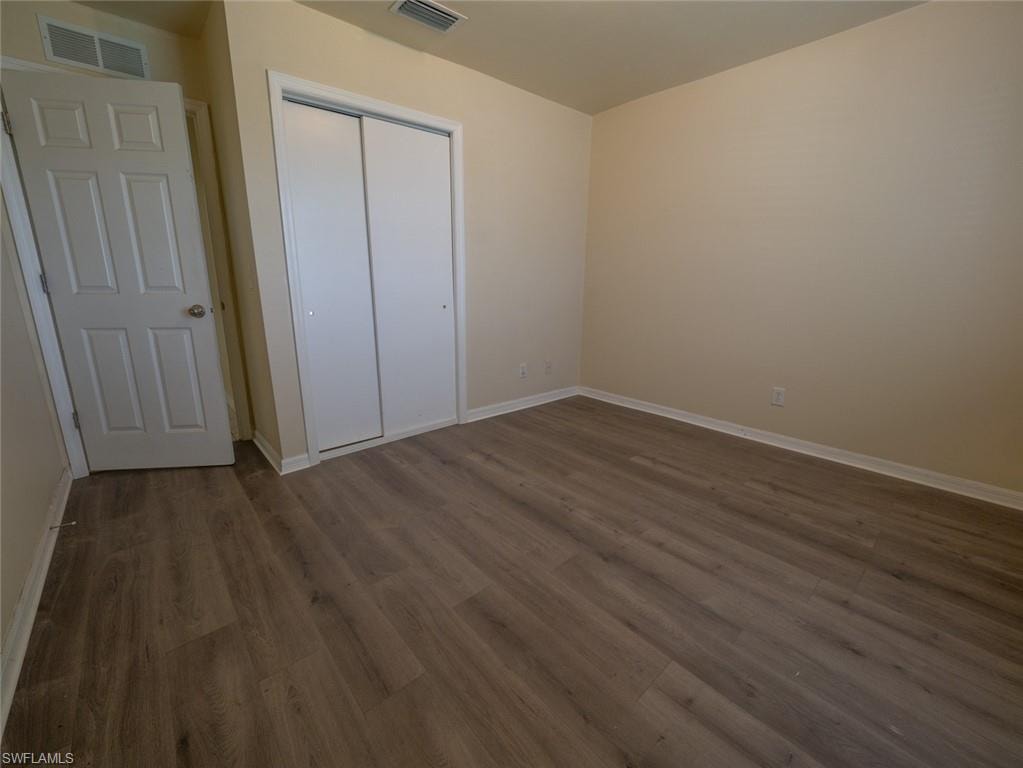 Unfurnished bedroom with a closet and dark hardwood / wood-style floors