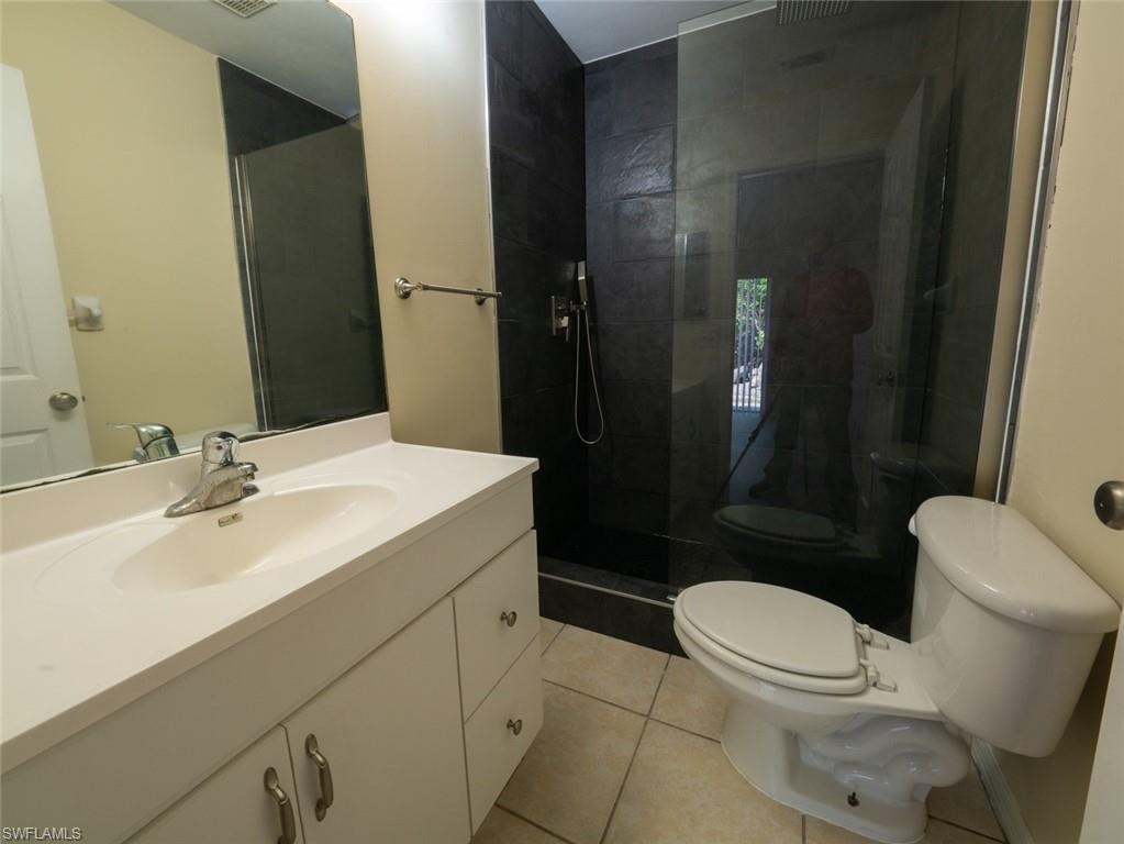 Bathroom with tile patterned flooring, vanity, toilet, and a shower with shower door